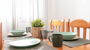 A dining table set with plates, bowls, a mug, and a glass pitcher, accompanied by a woven basket with a plant. - Apartment in the center of Nerja with pool (Nerja)