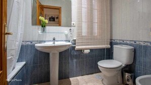 Et badeværelse med håndvask, toilet og et spejl med et billede i ramme.