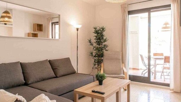 A modern living room with a grey sofa, a wooden coffee table, a potted plant, and a large mirror on the wall. - Modern two bedroom apartment in Nerja center (Nerja)