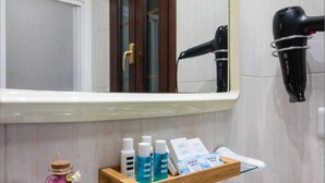 A bathroom with a mirror, a hairdryer, a shelf with toiletries, and a decorative jar. - P3. Moderno Apartamento en el Centro de Nerja (Nerja)