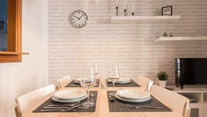 A dining area with a brick wall, a clock, and a TV. - P3. Moderno Apartamento en el Centro de Nerja (Nerja)