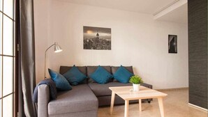 A modern living room with a grey sectional sofa, a small wooden coffee table, and a cityscape painting on the wall. - P3. Moderno Apartamento en el Centro de Nerja (Nerja)