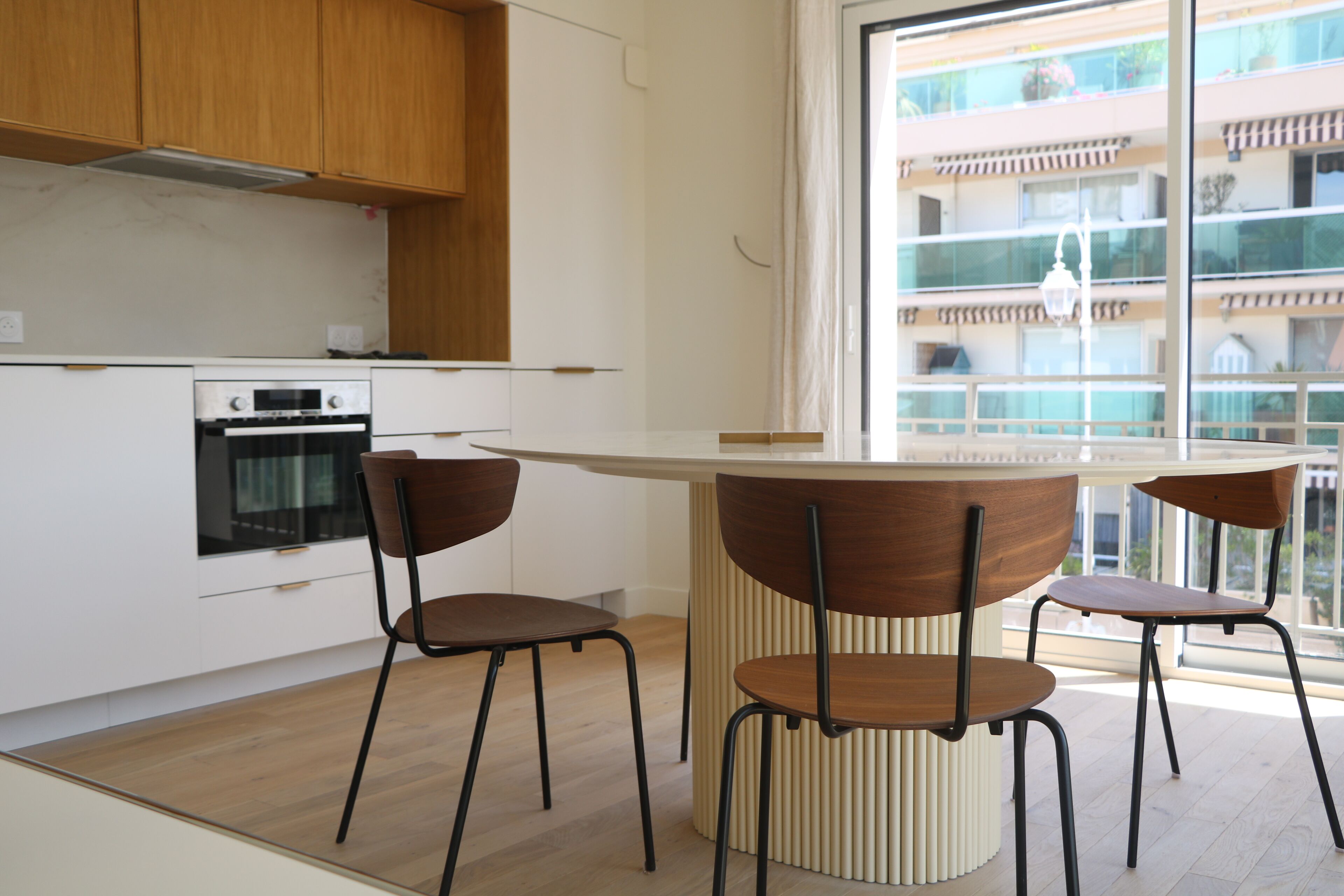 Une cuisine moderne avec des meubles en bois, un four encastré et un îlot central doté de chaises.