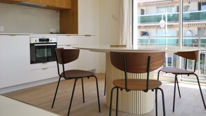 A modern kitchen with wooden cabinets, a built-in oven, and a central island with chairs.