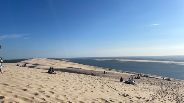 A desert landscape with sand dunes and a beach.