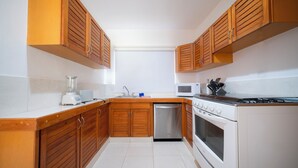 A kitchen with wooden cabinets, a dishwasher, a microwave, and a stove.