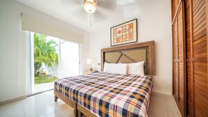 A bedroom with a bed, a ceiling fan, a window, and a door.