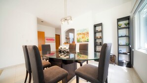 A modern dining area with a glass table and four upholstered chairs.