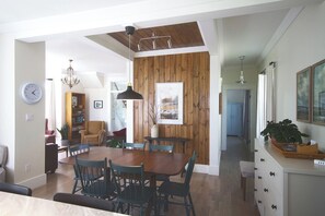 A dining area with a wooden table and chairs, a clock, and a bookshelf.