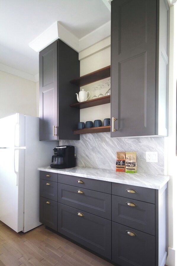 A kitchen with dark cabinets, a white refrigerator, and a marble countertop.