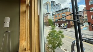 Une vue par la fenêtre, donnant sur un paysage urbain avec des bâtiments et une rue.