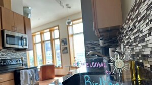 Une cuisine accueillante, avec un panneau de bienvenue, un four à micro-ondes, une cuisinière et une planche à découper en bois.
