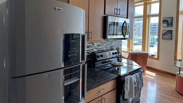 Una cocina moderna con electrodomésticos de acero inoxidable, armarios de madera y un amplio ventanal con vistas a la ciudad.