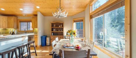 A spacious kitchen with wooden cabinets, a large island, and a dining area with a table set for two.
