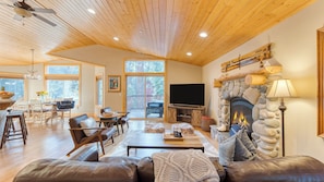 A cozy living room with a stone fireplace, leather furniture, and a large TV.