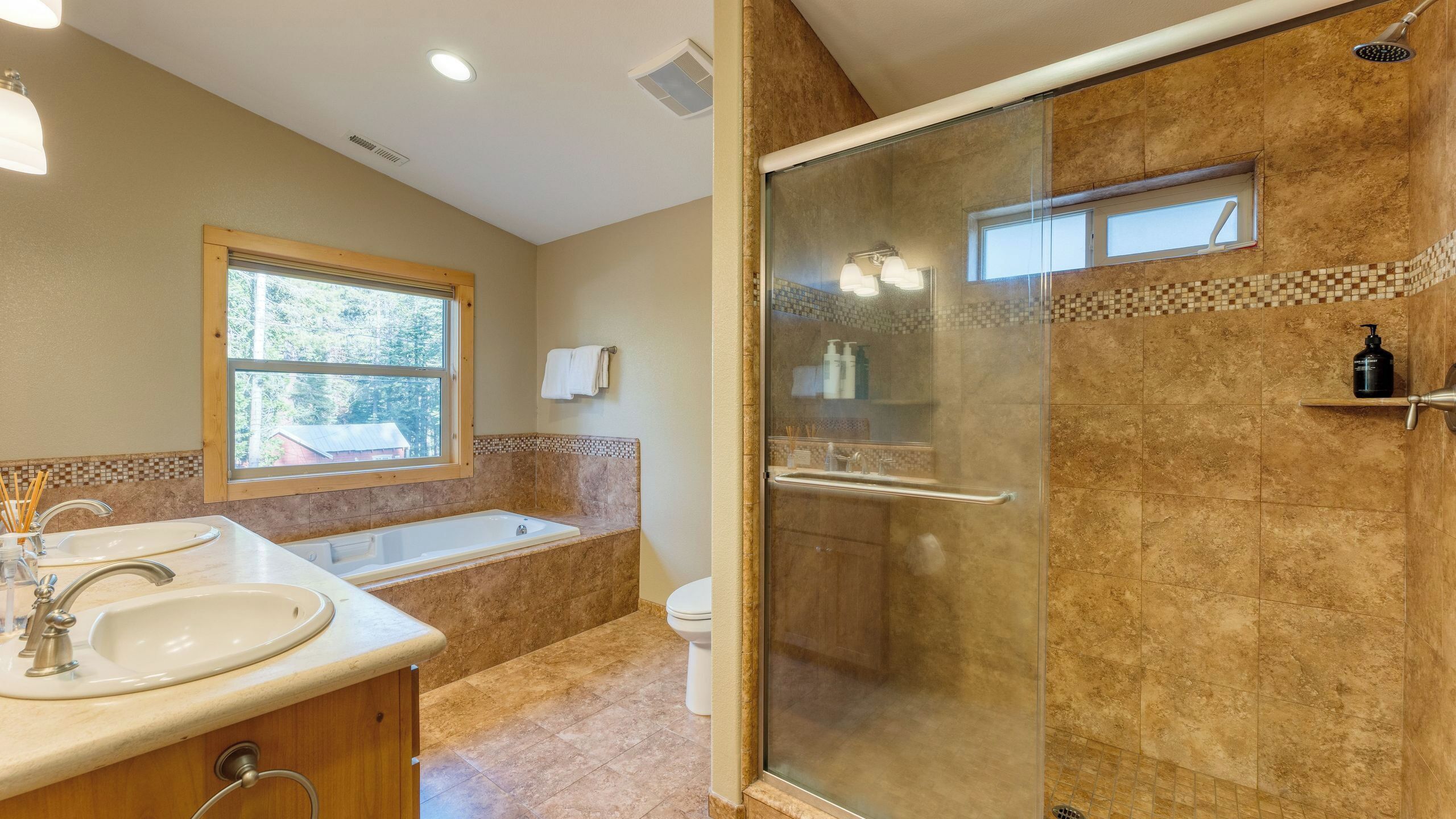 A bathroom with a glass shower, a bathtub, and a sink.