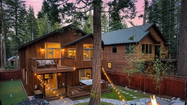 Une cabane en bois à deux étages, dotée d’une terrasse, d’un foyer et d’un espace patio.