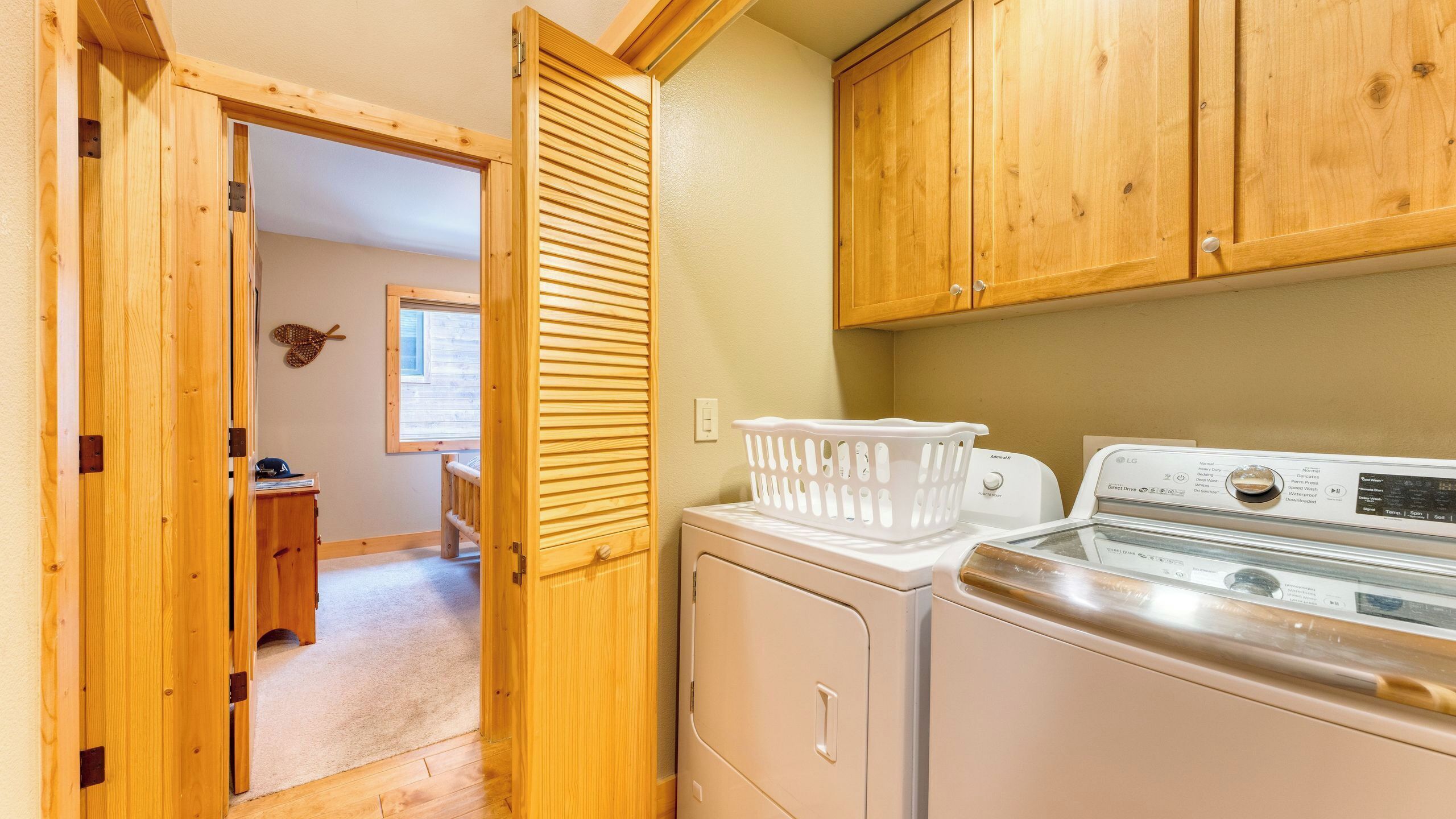 A laundry room with wooden cabinets, a washing machine, and a dryer.