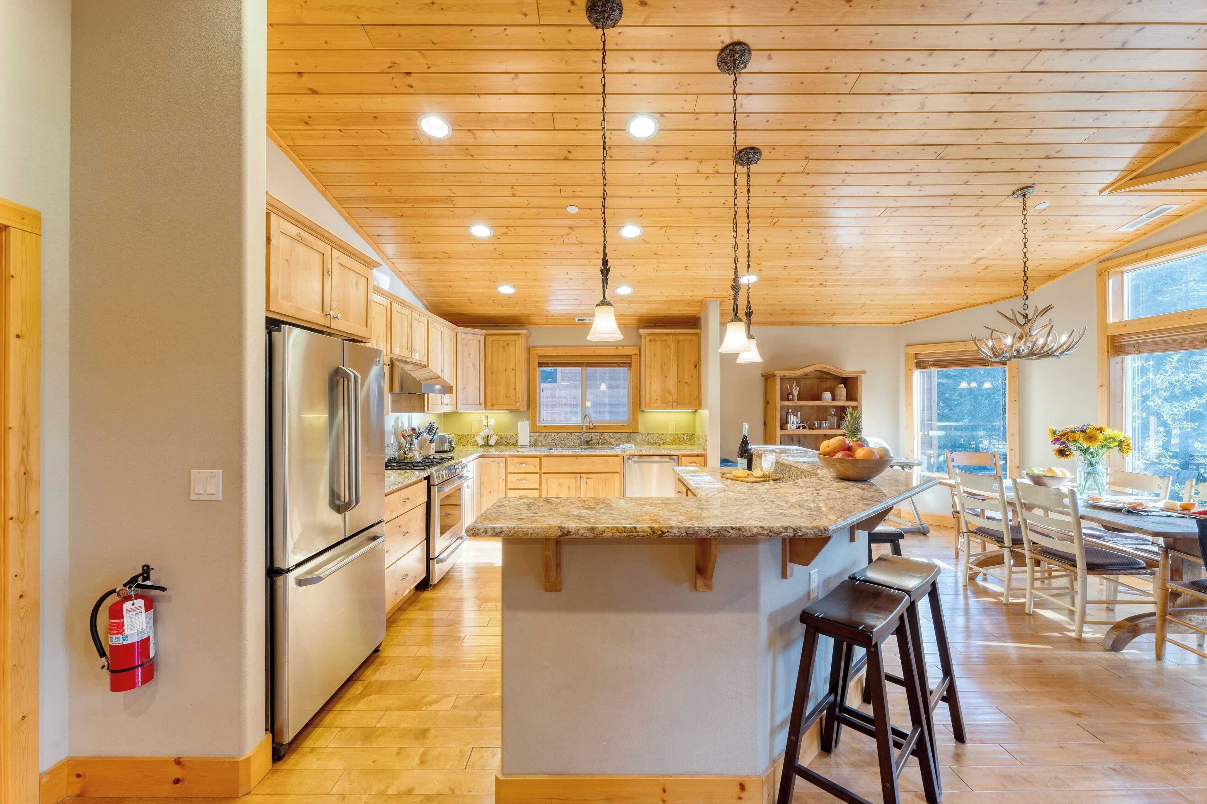 A spacious kitchen with wooden cabinets, a central island, and pendant lighting.
