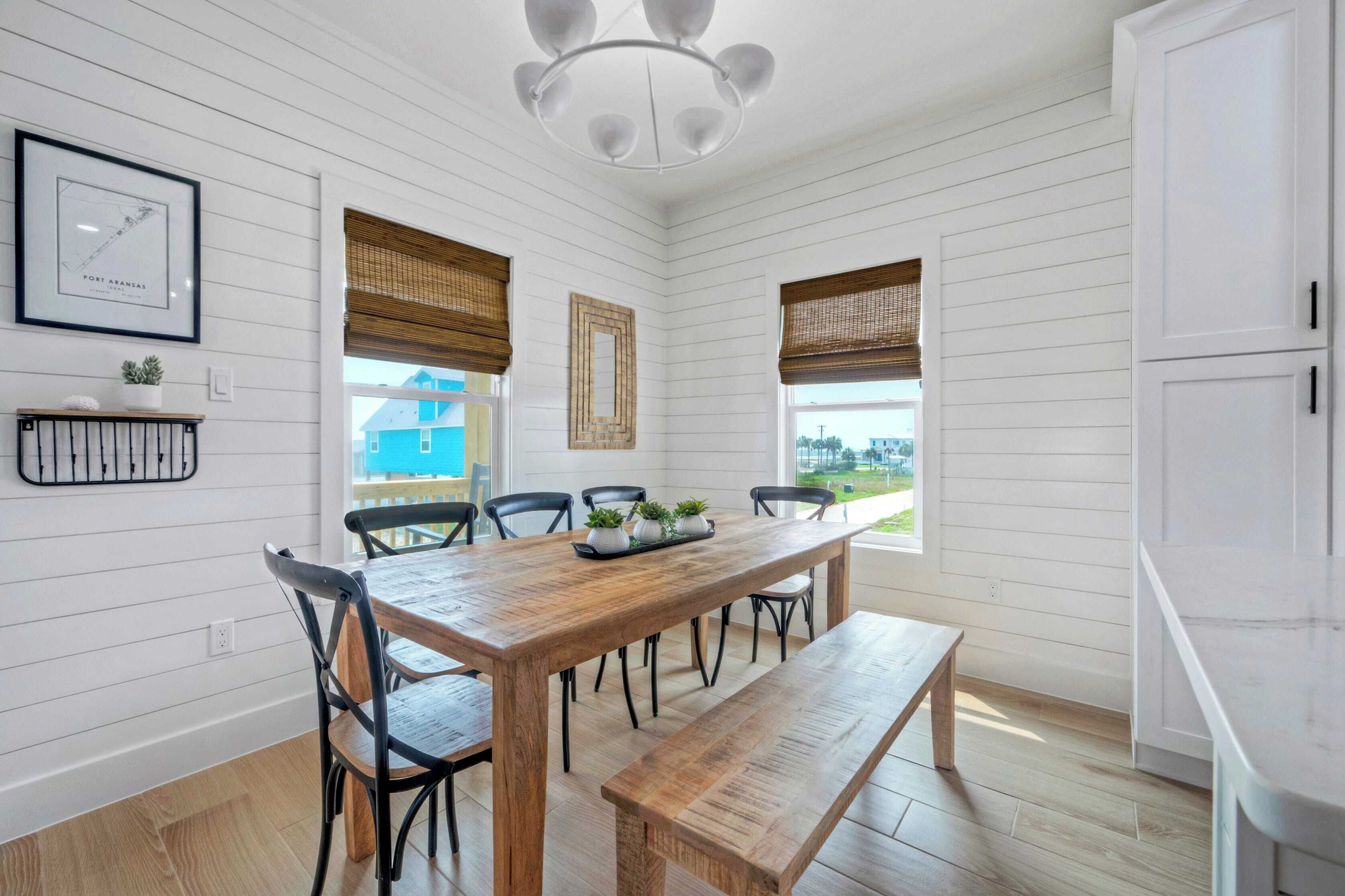 A dining area with a wooden table, six chairs, a bench, and a chandelier.