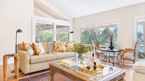 A modern living room with a sofa, coffee table, and a dining area with a chair and table.