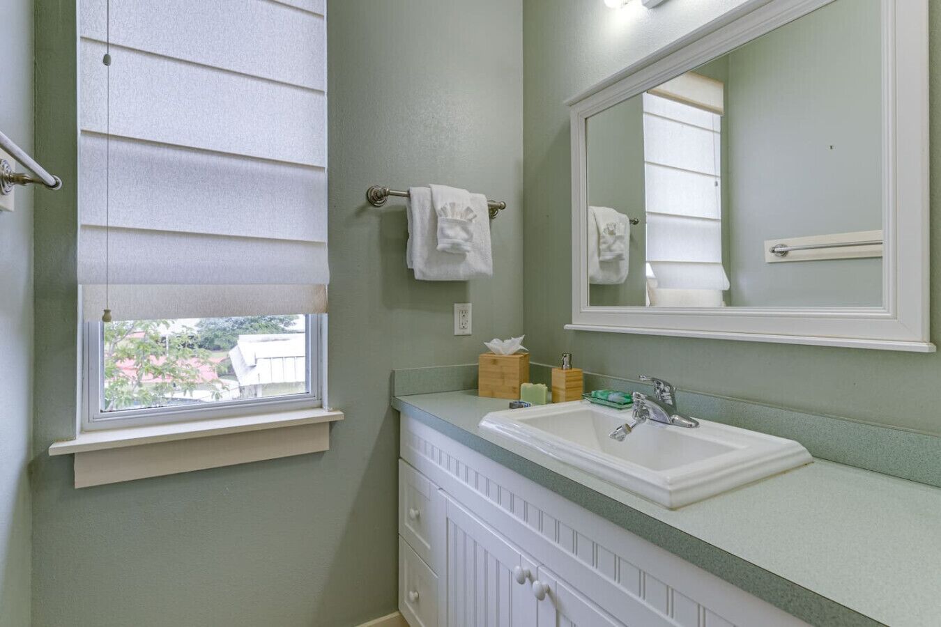 A bathroom with a window, a sink, a mirror, and a vanity with drawers.