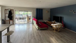 Un'ampia zona giorno con divano, tavolo da pranzo e televisore.