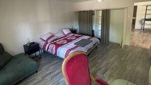 Una camera da letto con un letto, un divano verde, una sedia di legno e un tavolino.