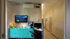 Moderni toimistotila, jossa on turkoosinvärinen työpöytä, kaksi näyttöä ja seinälle asennettu televisio, jolla esitetään diaesitys.