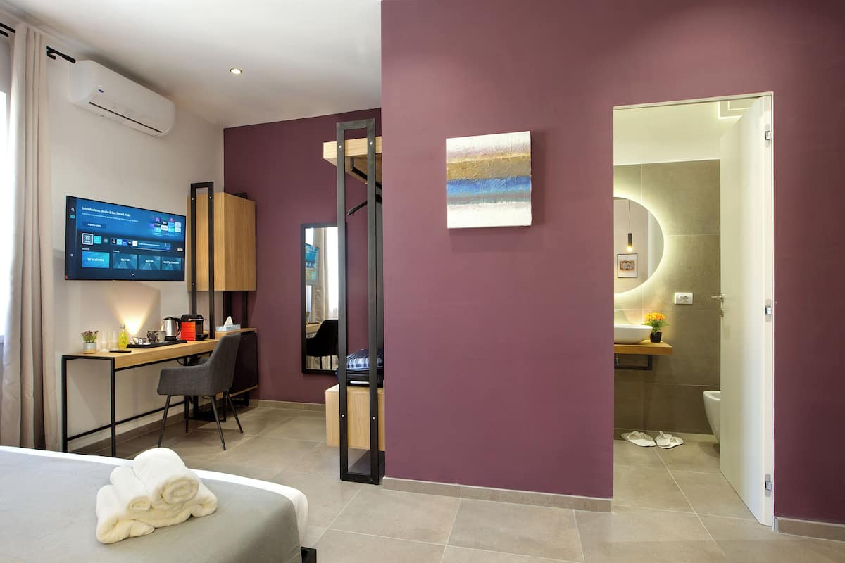 Une chambre d’hôtel moderne équipée d’un lit, d’un bureau et d’un téléviseur affichant un système de gestion hôtelière.