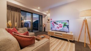 Una sala de estar moderna con sofá, televisor y lámpara.