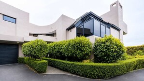 A modern building with a garage, neatly trimmed hedges, and a clear sky.