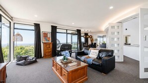 A modern living room with a leather sofa, a wooden coffee table, and a view of the outdoors.