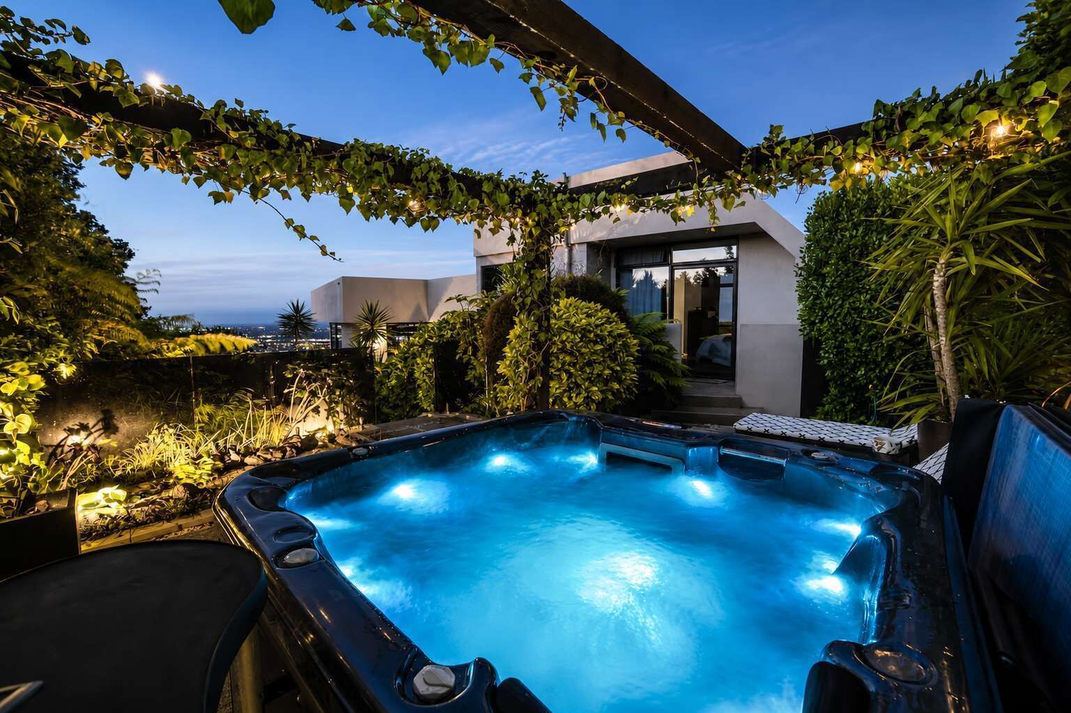 Un jacuzzi rodeado de vegetación, con un edificio al fondo.