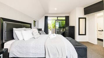 A modern bedroom with a large bed, a desk, and a wardrobe.