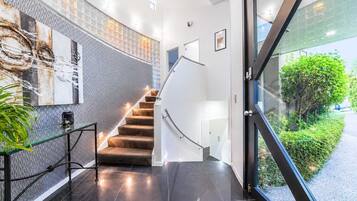 A modern interior with a glass door leading outside, a staircase with a white railing, and a wall with a textured pattern.