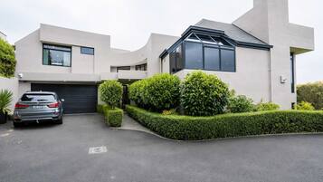 A modern two-story house with a garage, a driveway, and well-maintained hedges.