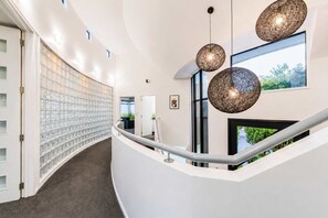 A modern interior with a curved staircase, glass block wall, and pendant lighting. - City Views | 4BR | Sleeps 10 | Christchurch (Christchurch)