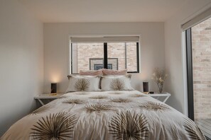Un dormitorio con una cama grande, una ventana y una pared de ladrillo.