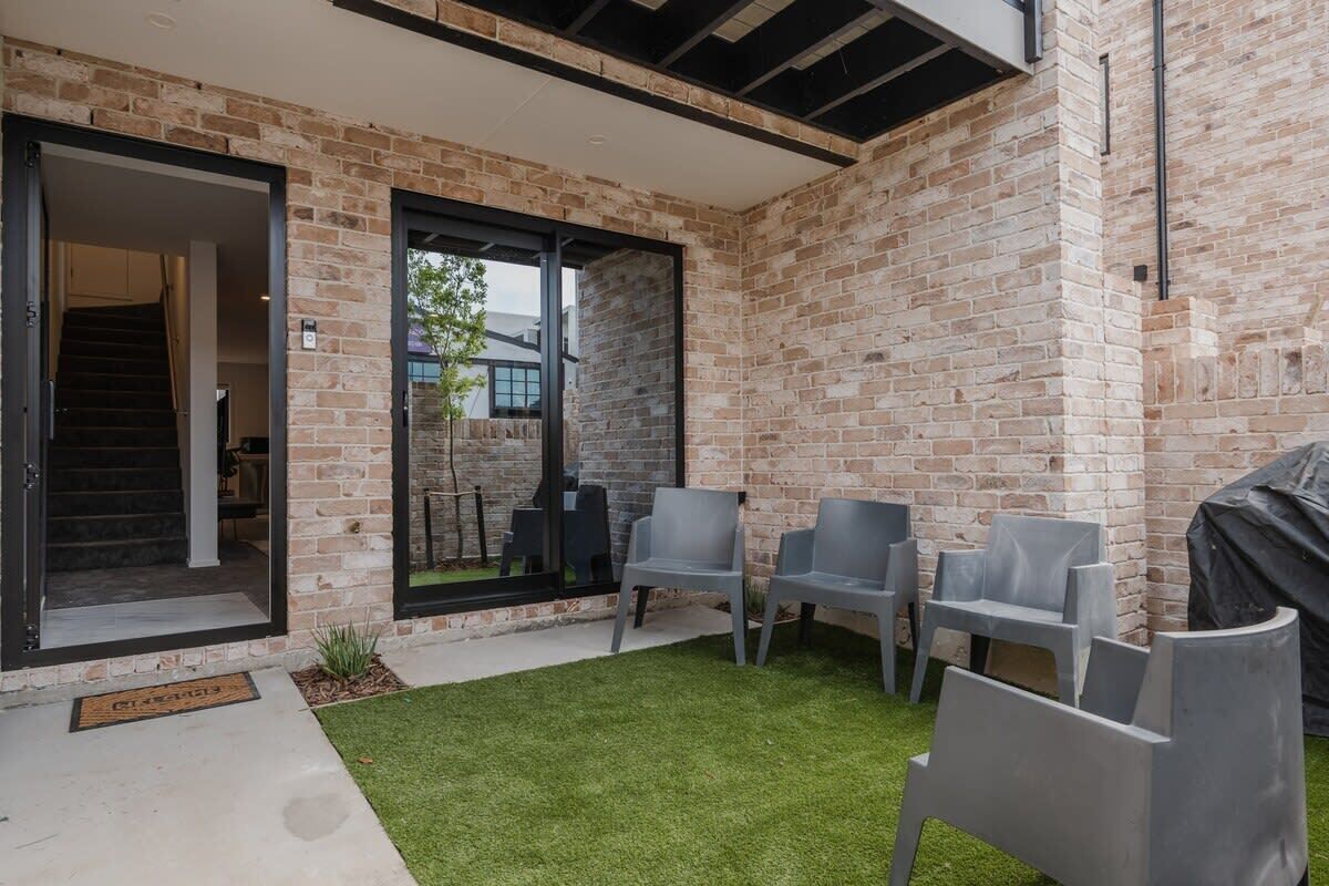 A patio area with a brick wall, a covered seating area, and a door leading to an interior space.