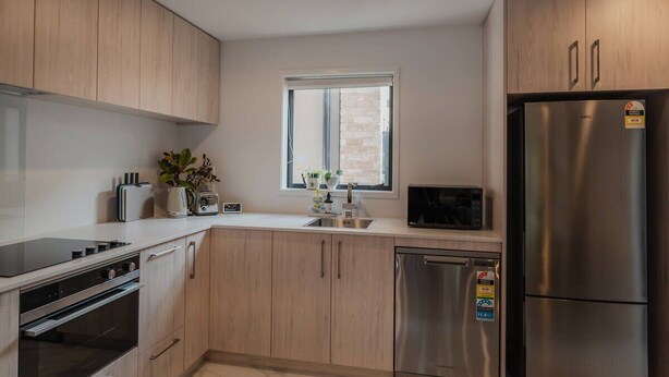 Une cuisine moderne avec des meubles en bois, un réfrigérateur en acier inoxydable et un four encastré.