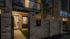 Un bâtiment moderne avec une façade en briques, une entrée en verre et une enseigne indiquant l’adresse, bien visible.