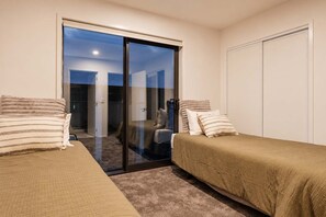 Ein Schlafzimmer mit zwei Betten, einer Schiebetür zum Balkon und einem Kleiderschrank.