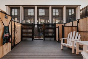 Une terrasse en bois avec une porte, un banc et une chaise.