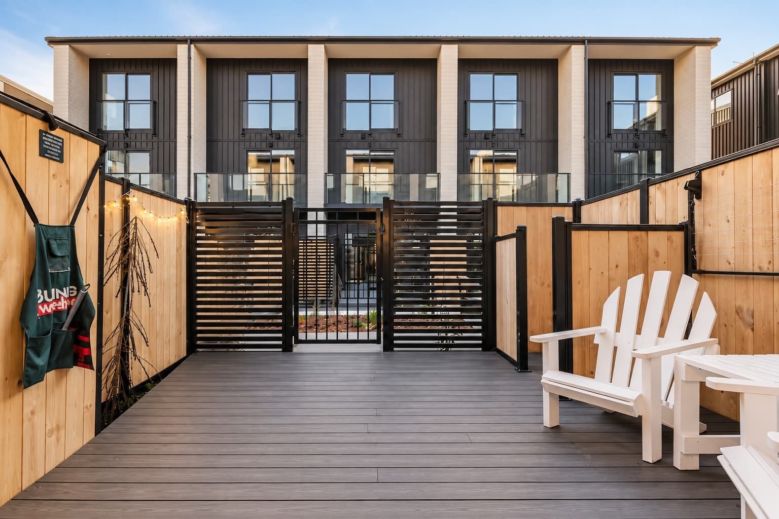 Eine Holzterrasse mit einem Tor, einem weißen Stuhl und einem Tisch.