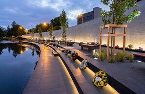 A serene outdoor memorial area with a reflective pool, benches, and floral tributes.