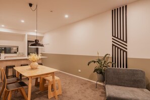 Un salon moderne comprenant un coin repas, un canapé gris, une plante en pot et un panneau décoratif mural.