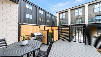 A patio area with a grill, table, and chairs.
