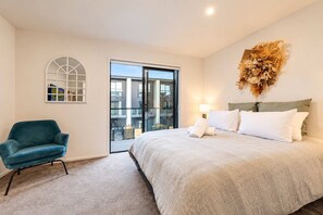 A bedroom with a bed, a chair, a window, and a decorative wall piece.