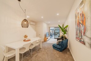 A modern interior with a dining area, a sofa, and a large abstract painting. - Downtown Bliss - 4-BR Retreat Amidst the Cityscape (Christchurch Central City)